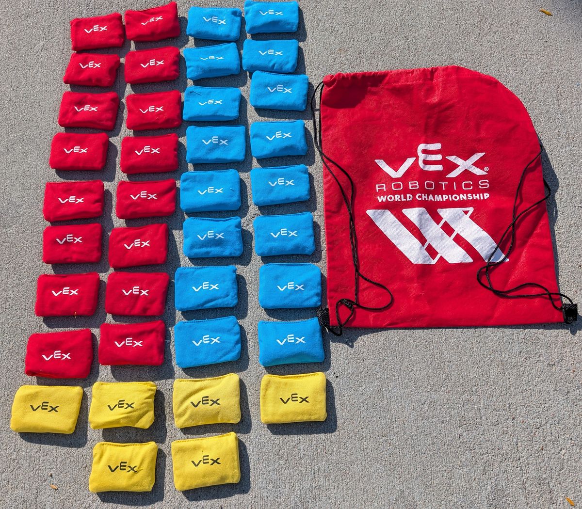 A field's set of bean bags laid out beside their drawstring bag: 16 red, 16 blue and 6 yellow