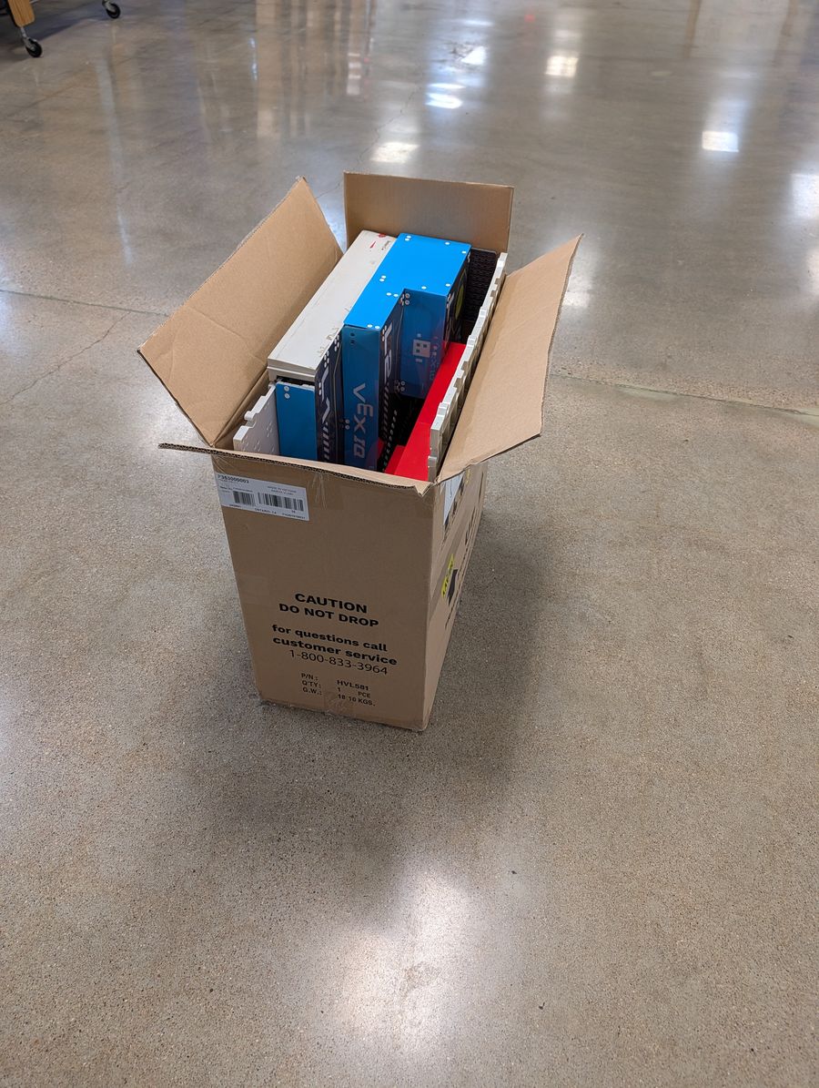A cardboard box holding a set of pyramid corner pieces standing on edge