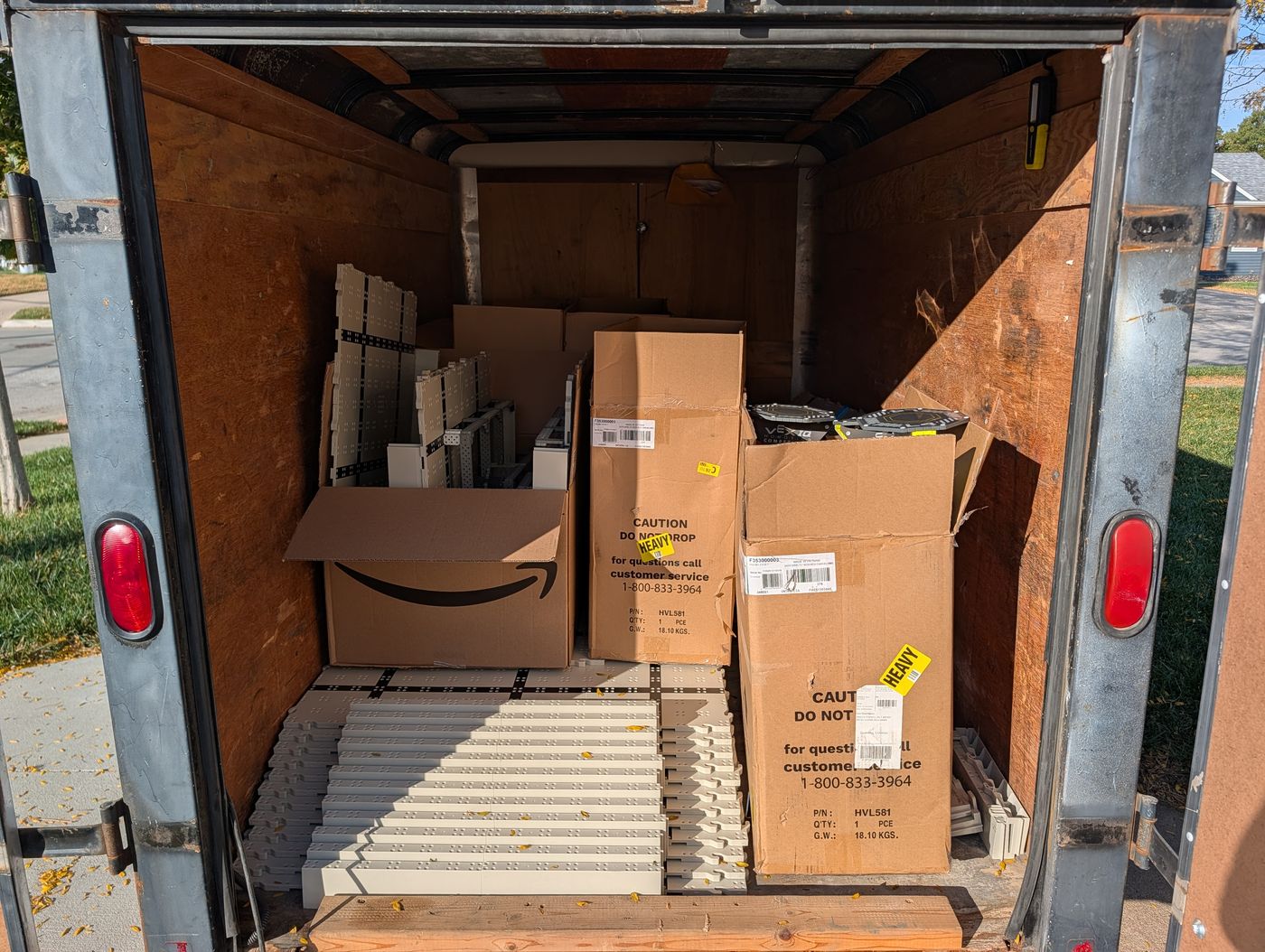 The loaded VEX IQ trailer seen from the rear door: game element boxes at the front, floor sections and wall strips stacked flat behind them