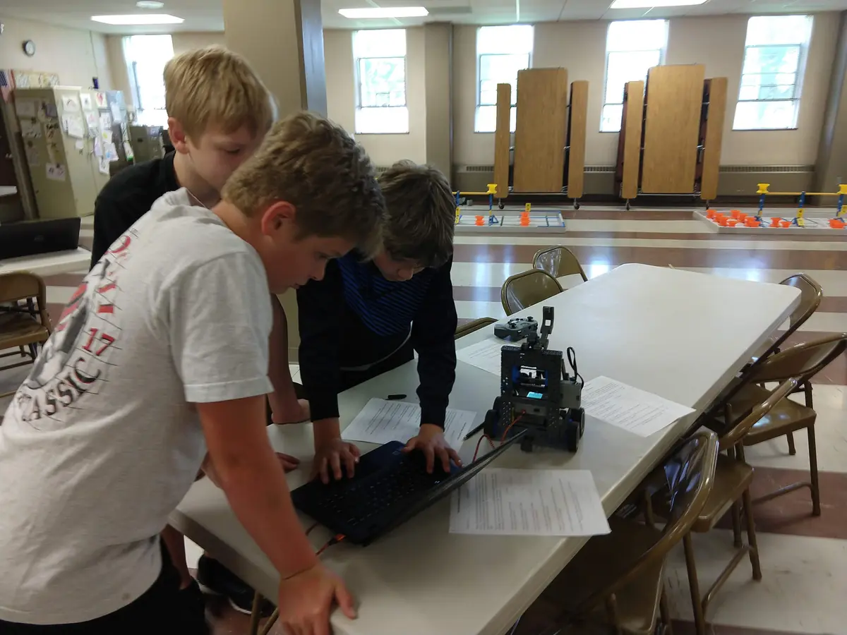 Students programming their VEX IQ robot on a laptop during a session
