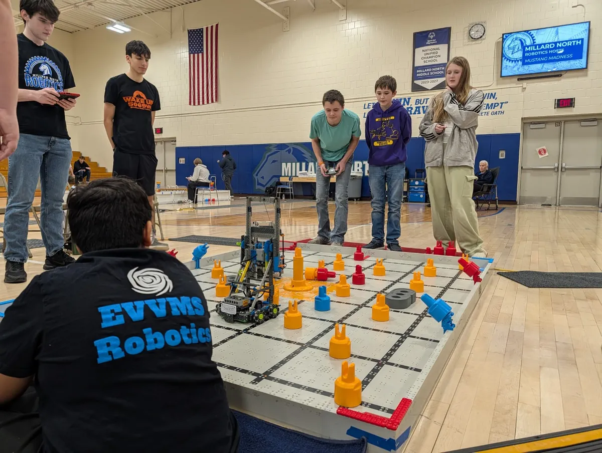 Students driving robots during a VEX IQ tournament match in a gym
