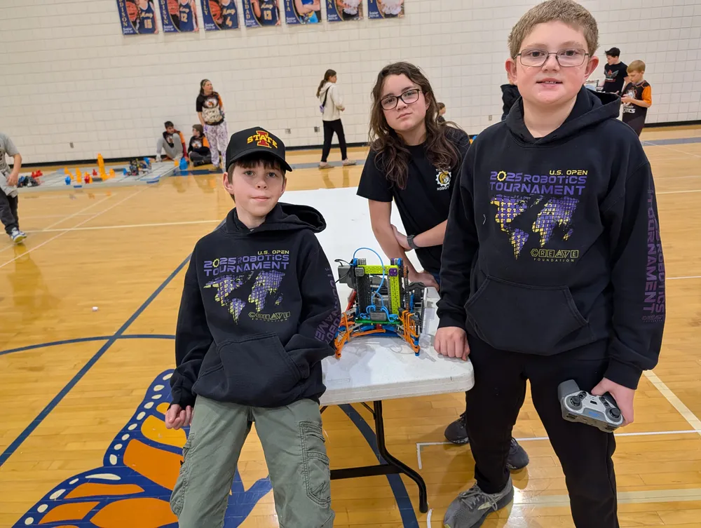 A mentor working with a student team and their VEX IQ robot at a tournament