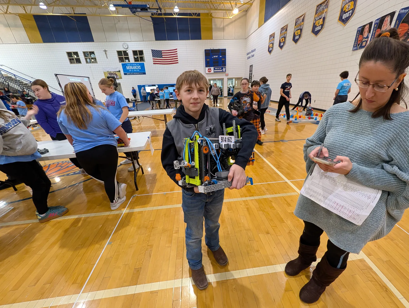 A student carrying his VEX IQ robot to a judge at a tournament
