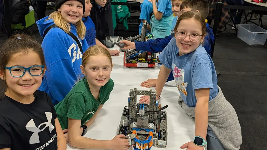 Four girls smiling with the robot they built at a Nebraska VEX IQ tournament