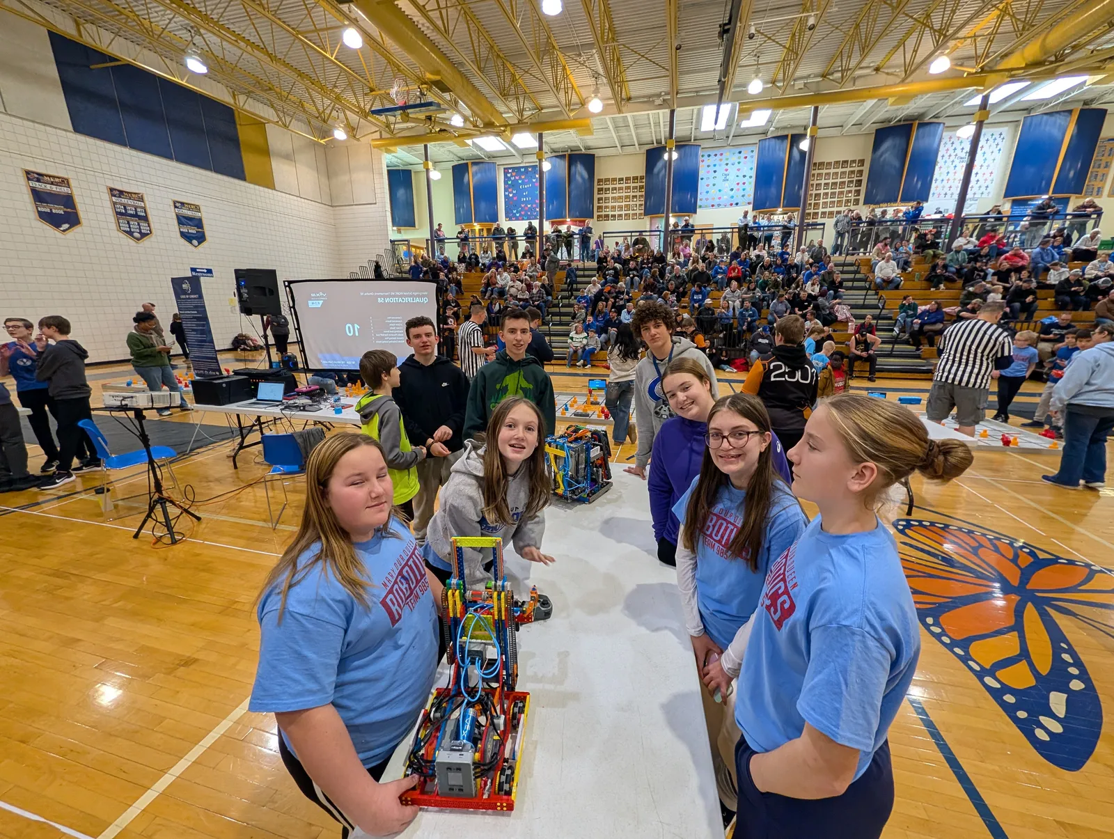 A student team kneeling with their VEX IQ robot at a tournament